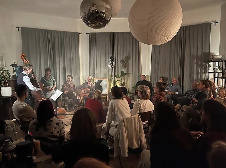 Bezoekers in een woonkamer kijken naar muzikanten die samen spelen